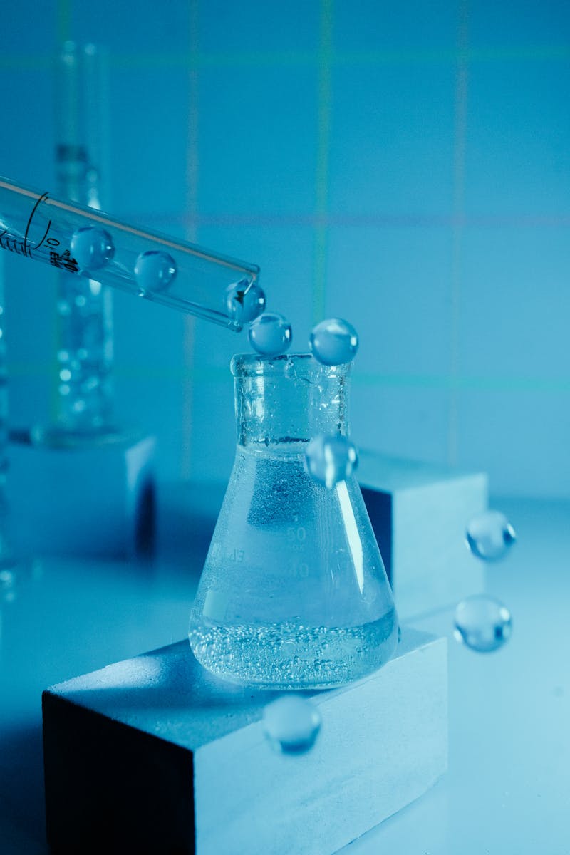 About McBoeck 1 Laboratory experiment showcasing a beaker with bubbling liquid and pipette against a blue backdrop.