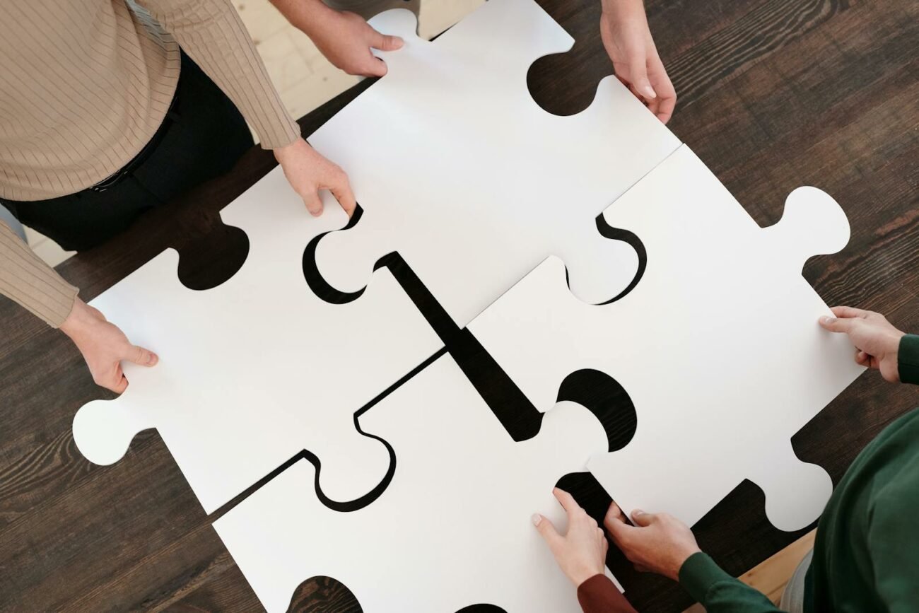 Photo by Diva Plavalaguna Group collaborating on assembling large puzzle pieces symbolizing teamwork and unity.