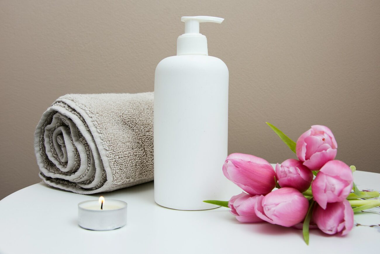 Photo by Camille Brodard white plastic pump bottle beside pink tulips and gray towel