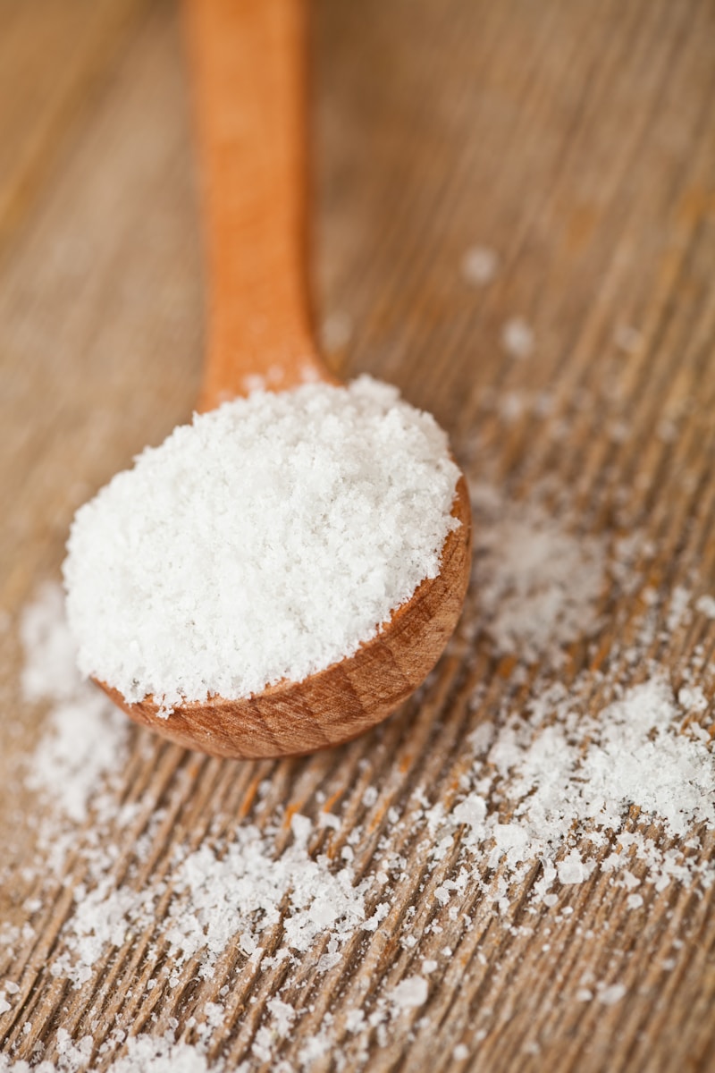 Food + Beverages 1 A wooden spoon filled with sugar on top of a wooden table