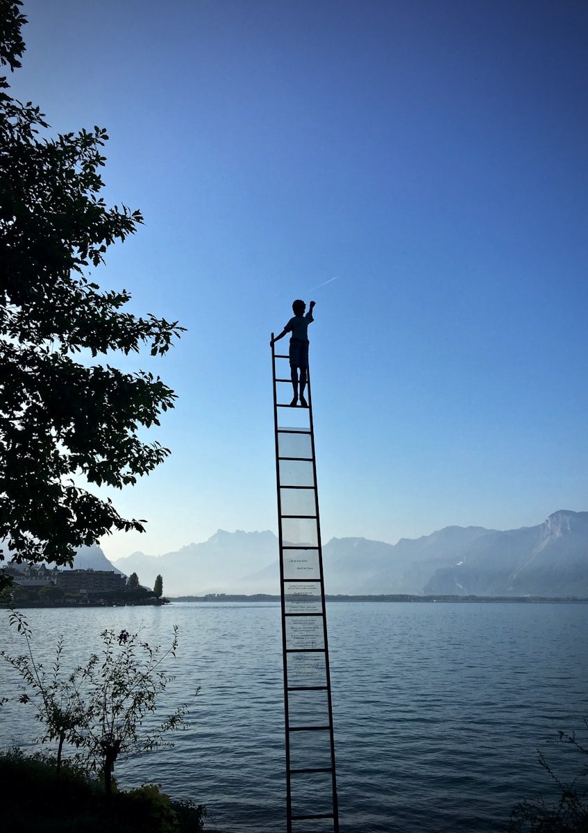 Photo by Armand Khoury boy on ladder under blue sky